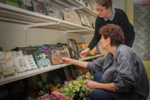 Femmes choisissant des plaques funéraires et souvenirs dans une boutique d'obsèques.