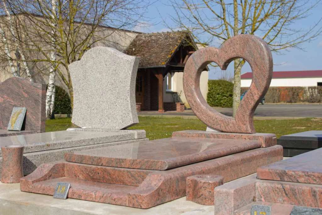 Monument funéraire en granit rose avec une stèle découpée en forme de cœur.