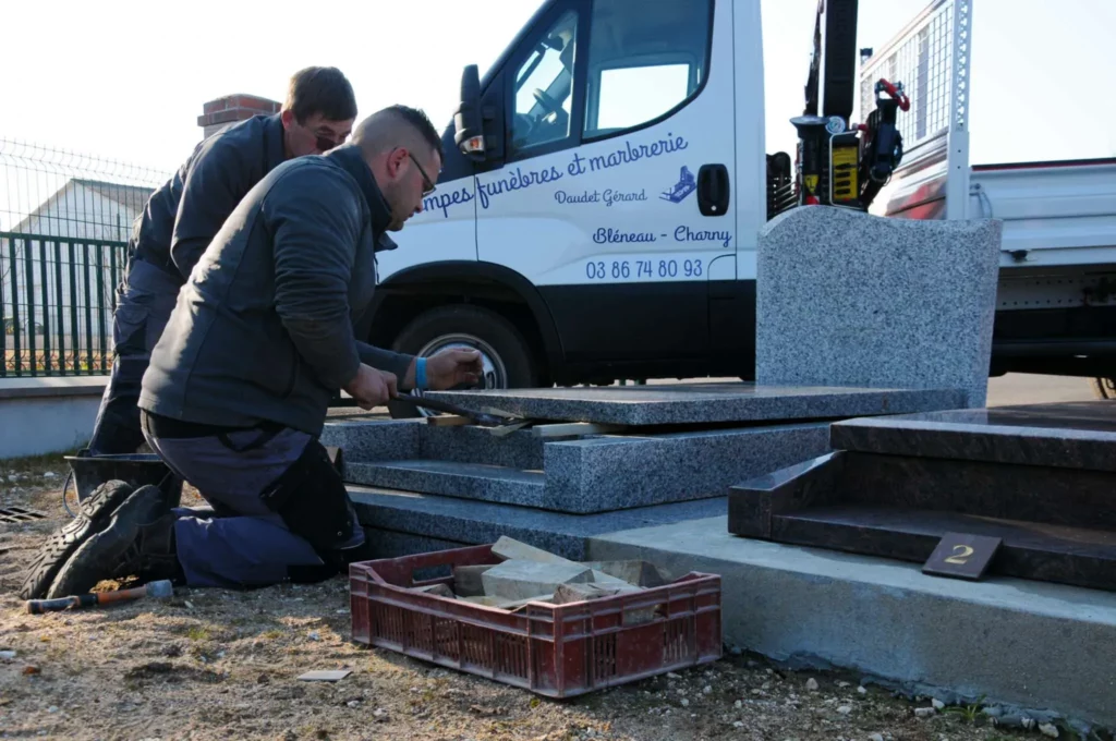 Marbriers en plein travail d'installation d'un monument funéraire en granit.